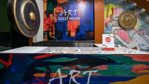 A room with a colorful abstract painting, a large circular object, and a sign reading "ART GUEST HOUSE". - Hotel O Art Guest House Syariah (Yogyakarta)