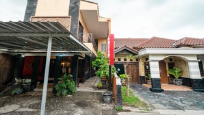 A courtyard with a covered seating area, potted plants, and a building with a tiled roof. - Hotel O Art Guest House Syariah (Yogyakarta)