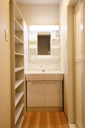 Une petite salle de bain avec un lavabo blanc, un miroir et des étagères.