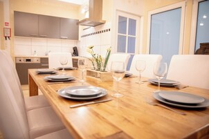 Un comedor con una mesa de madera dispuesta para cuatro personas, con platos, vasos y cubiertos.