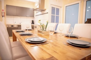 A dining area with a wooden table set for four, equipped with plates, glasses, and cutlery. - Zythogite 8 personnes (Tintigny)