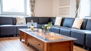 Una sala de estar moderna con una mesa de centro de madera, un sofá gris y una ventana con cortinas.