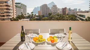 Une table dressée avec des assiettes de fruits et des verres à vin, donnant sur un paysage urbain avec des palmiers et des immeubles.