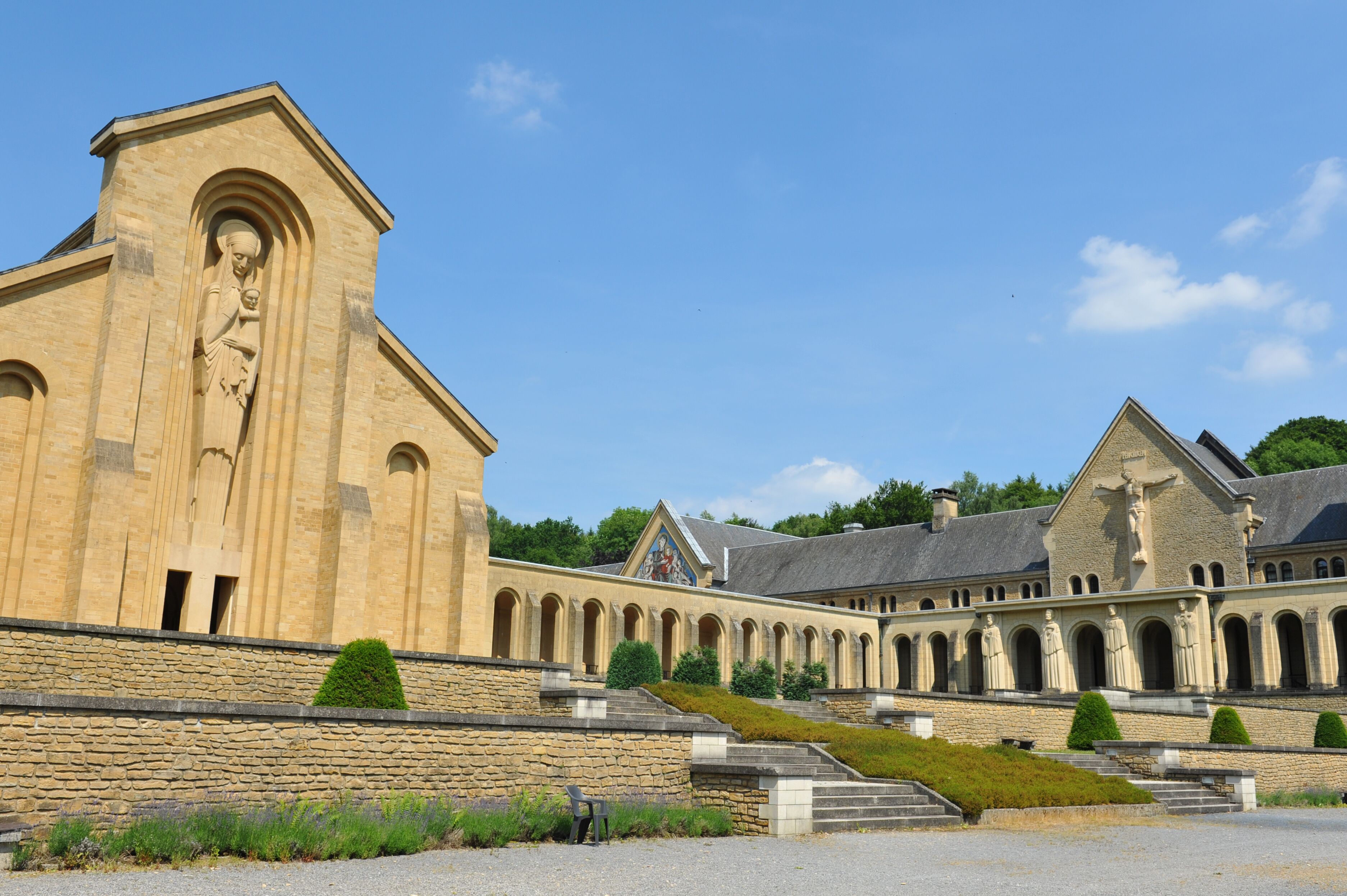 A historic building with a prominent statue, a series of arches, and a stone staircase leading to the entrance.
