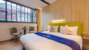 A hotel room with a large bed, a desk, two chairs, and a window with a view of buildings. - Mutsun B&B (Jiaoxi)