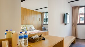 A hotel room with a wooden desk, a bed with pillows, a chair, a window with curtains, and a wall-mounted TV. - Mutsun B&B (Jiaoxi)