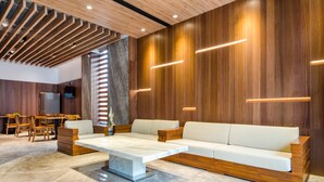 A modern interior with a wooden accent wall, a white sofa, and a marble coffee table. - Mutsun B&B (Jiaoxi)