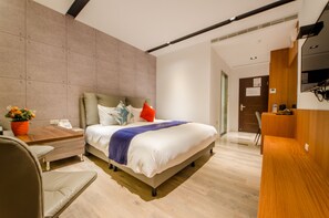 Una habitación de hotel moderna con una cama grande, un escritorio y una silla.