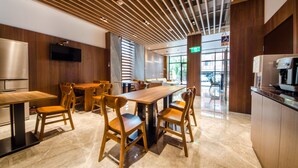 A modern dining area with wooden furniture, a large table, and a kitchen area with a refrigerator and coffee machine. - Mutsun B&B (Jiaoxi)