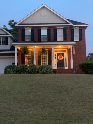A two-story brick house with a front porch, a garage, and a well-maintained lawn. - 4br Masters Rental 3.5 Miles from Augusta National (Martinez)