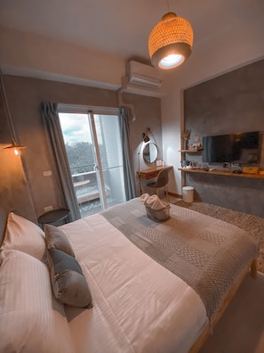 A hotel room with a large bed, a desk with a chair, a television, and a view of a snowy landscape through the window.