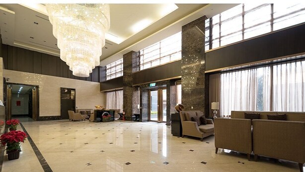 Eine geräumige Lobby mit hoher Decke, einer Kandelaber und einer Rezeption.