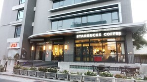 Ein Starbucks Coffee Store mit moderner Fassade, großen Fenstern und einem Sitzbereich im Freien.