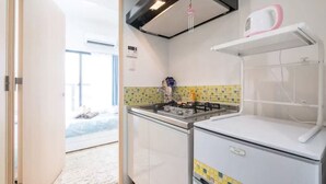 Une cuisine compacte équipée d’une cuisinière à gaz, d’un petit réfrigérateur et d’un four à micro-ondes. Une fenêtre offre une vue sur l’extérieur.
