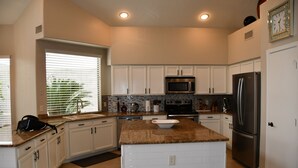 A modern kitchen with white cabinets, a granite countertop, stainless steel appliances, and a window with blinds. - Near Scottsdale Area, Minutes From High end Shopping Malls and Restaurants (Phoenix)