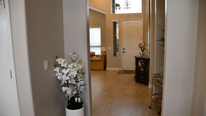 A hallway with a white vase of white flowers, a wooden door, and a small table with a vase of red flowers. - Near Scottsdale Area, Minutes From High end Shopping Malls and Restaurants (Phoenix)