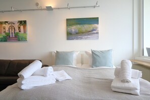A hotel room with a bed, a sofa, and a painting on the wall.