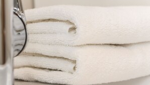 Une pile de serviettes blanches, soigneusement pliées, est posée sur une surface métallique.