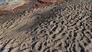 Ein Strand mit felsigem Ufer, einem Boot und einer bergigen Kulisse.