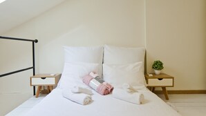 A neatly made bed with rolled towels and a small potted plant on a bedside table. - Stylish flat at Rothschild boulevard (Tel Aviv)