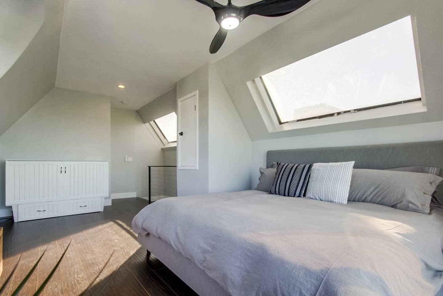 A bedroom with a large bed, a skylight, a radiator, and a view of the outside.