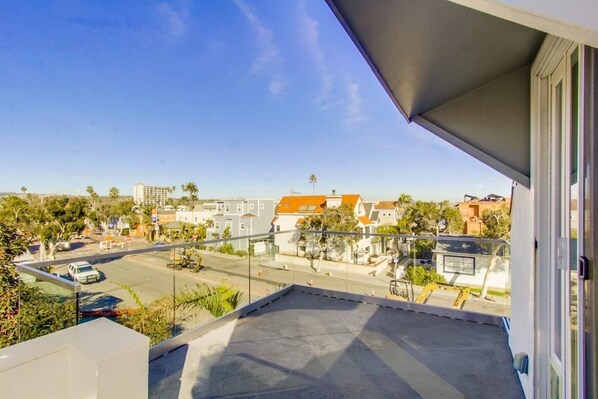 Un balcon donnant sur un quartier résidentiel, avec vue sur les maisons et les voitures garées.