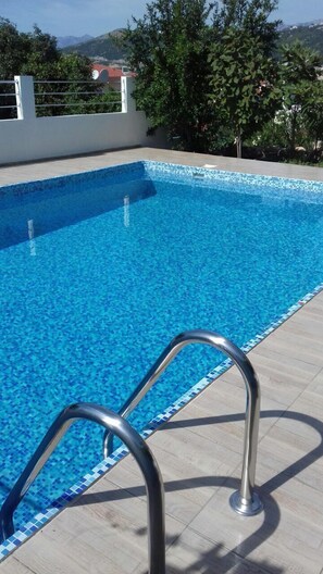 Una piscina al aire libre de temporada, sombrillas