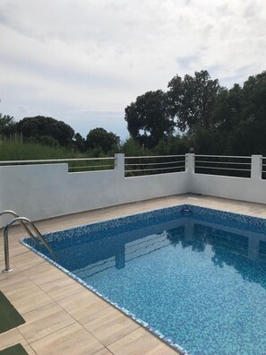 Una piscina al aire libre de temporada, sombrillas