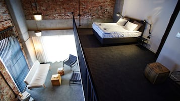 Una camera da letto in stile loft con un letto grande, un piccolo angolo salotto e vista sulla città.