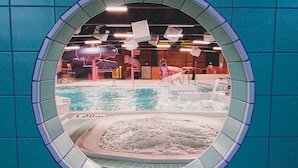 Una piscina interior con un jacuzzi, rodeada por un muro de azulejos.