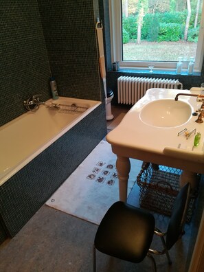 A bathroom with a bathtub, sink, and window.