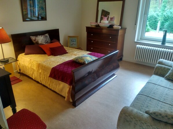A bedroom with a bed, dresser, and a window with a view of greenery. - B&B Golf Schilde (Schilde)