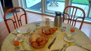 A dining table set with breakfast items including bread, pastries, cheese, and meats, with a view of a grassy area outside. - B&B Golf Schilde (Schilde)