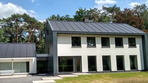 A modern two-story house with a flat roof, large windows, and a paved driveway. - B&B Golf Schilde (Schilde)