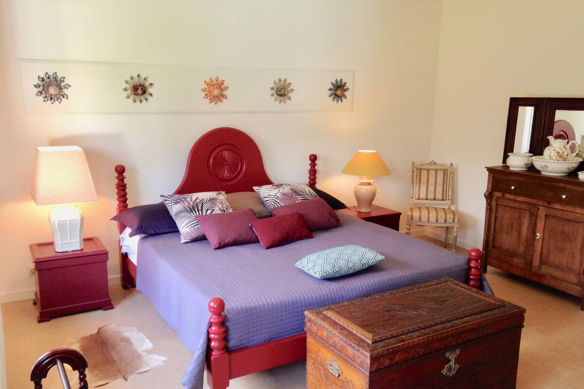 A neatly arranged bedroom with a bed, two bedside tables, a wooden chest, and a chair.