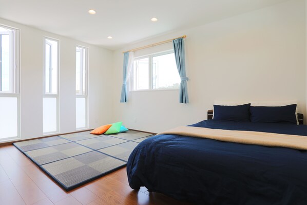 A room with a bed, a futon, a tatami mat, and a window with curtains. - Kahoo House (Nago)