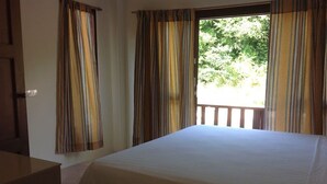 A room with a bed, a wooden desk, and a window with curtains.