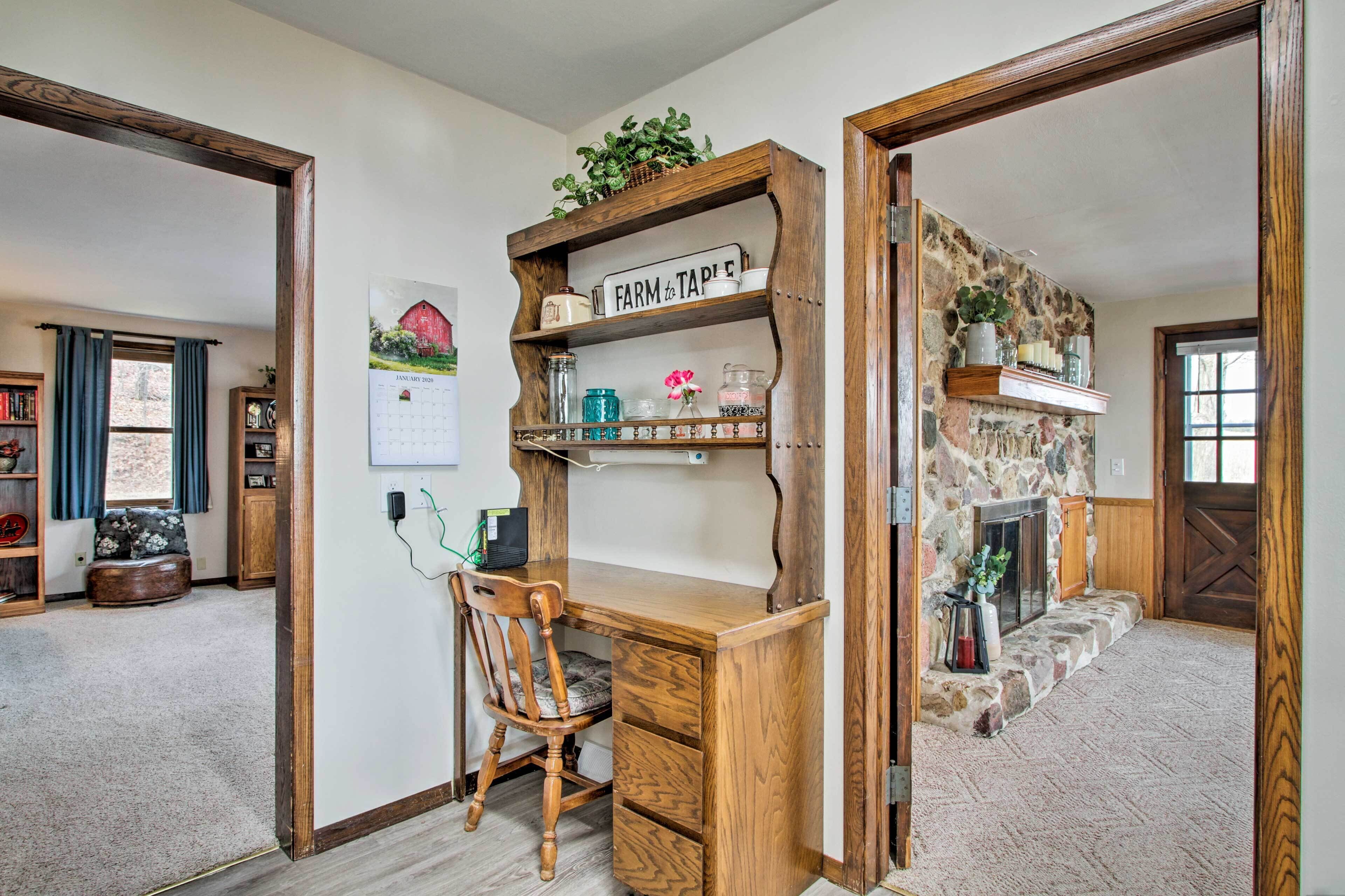 A rustic room with a wooden desk, a stone fireplace, and shelves with decorative items.