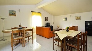 Un comedor con mesa y sillas de madera, un sofá y una televisión.