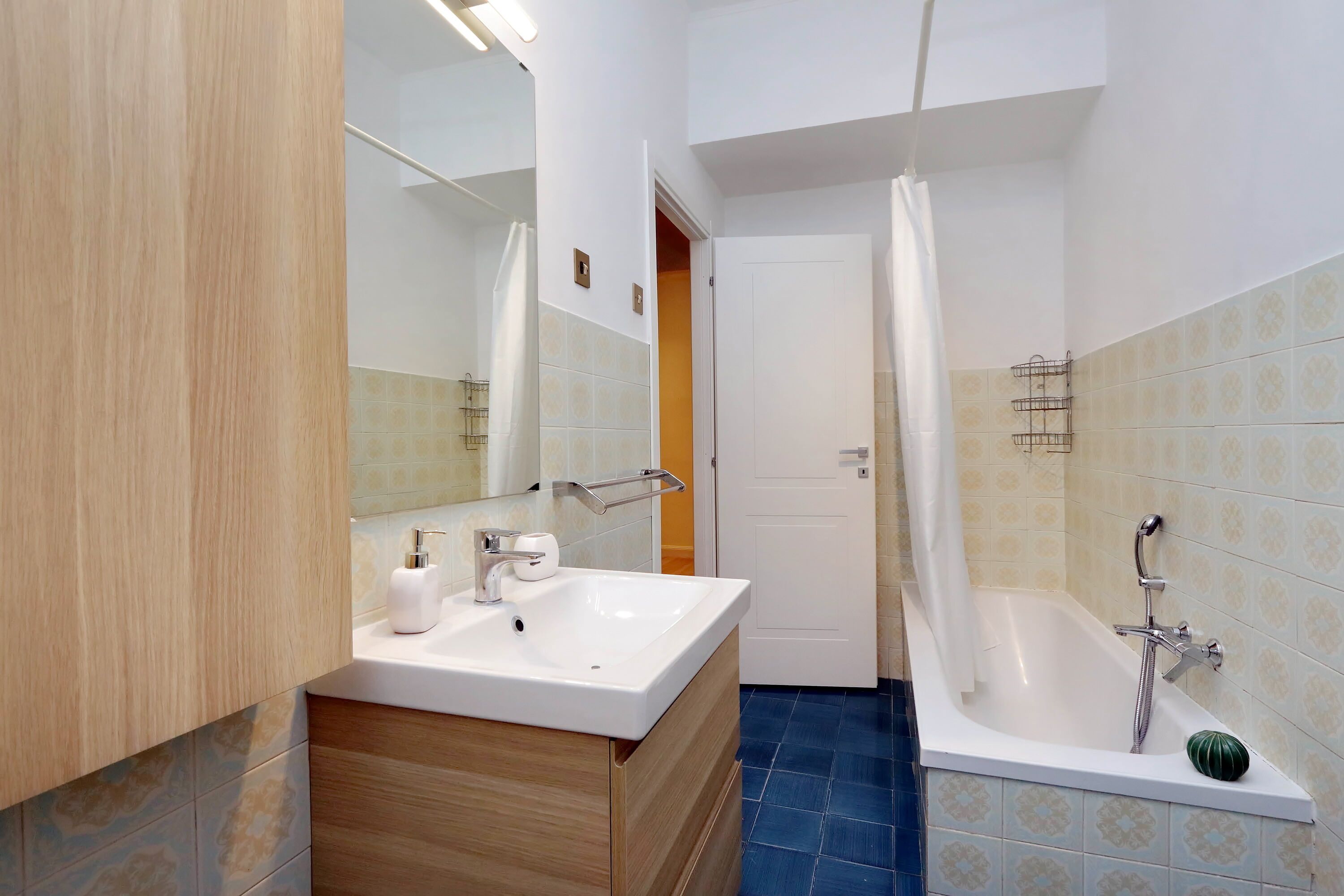 Un bagno con lavandino, specchio e vasca bianca.