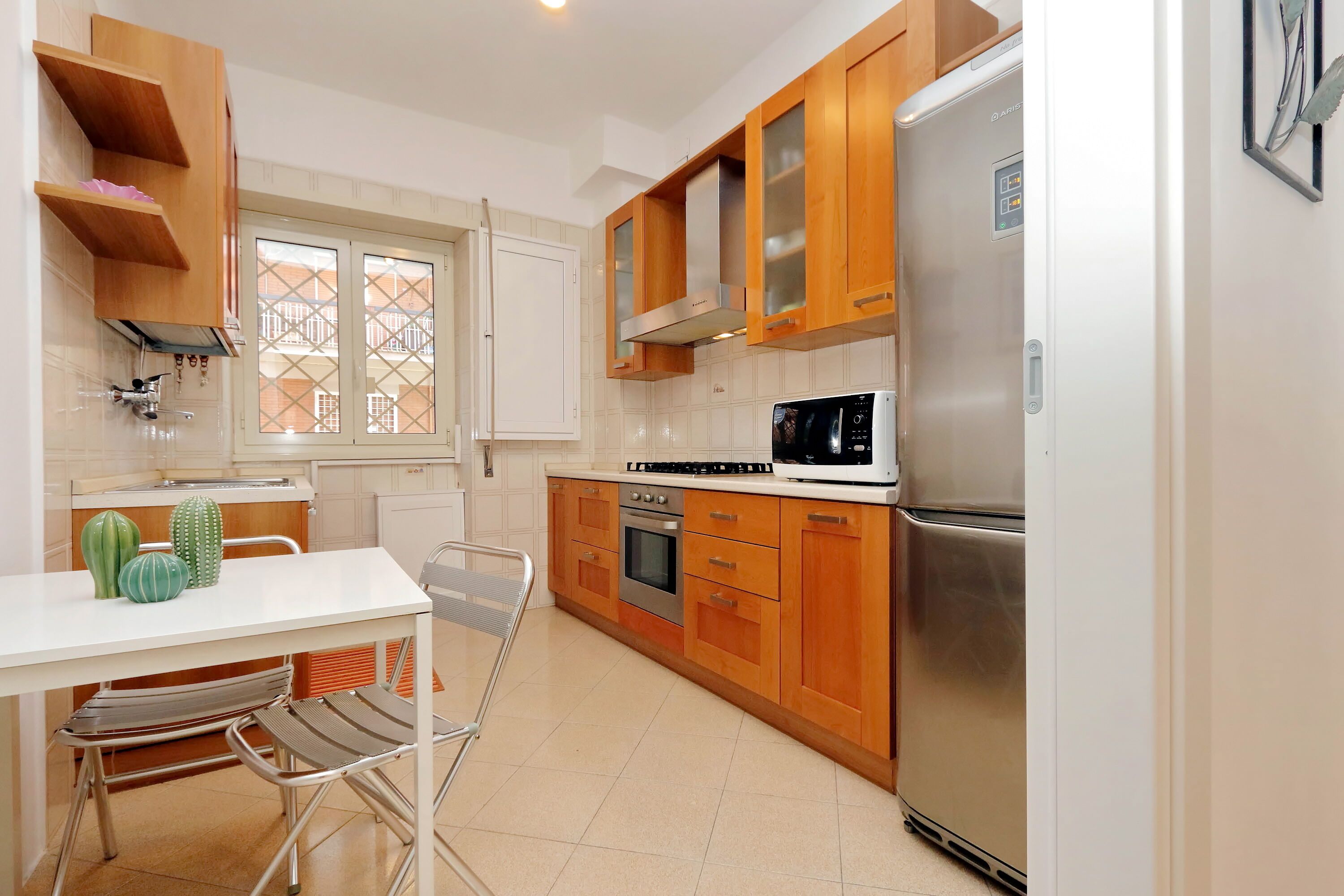 A modern kitchen with wooden cabinets, a stainless steel refrigerator, a microwave, and a gas stove.