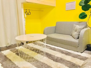 A room with a sofa, a round table, and a striped rug.