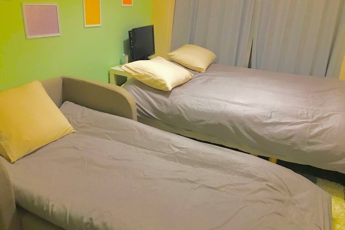 A room with two beds, a small bedside table, and a television on a stand.