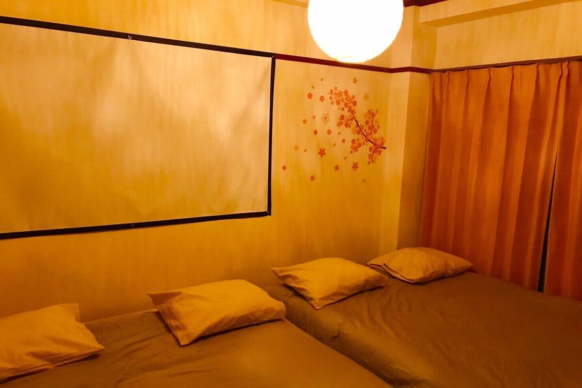 A room with two beds, a large window, and a wall decoration.