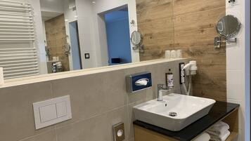 Une salle de bain moderne avec un grand miroir, un lavabo blanc et un porte-serviettes.
