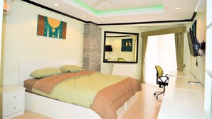 A bedroom with a bed, a desk, a chair, a ceiling fan, and a large mirror. - Sleek 1 bed Condo Jomtien (Pattaya)