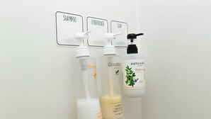 A bathroom with three bottles of shampoo, conditioner, and soap, each labeled with their respective names. - Guesthouse Daikokucho Ekimae (Osaka)
