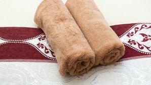 Two rolled towels on a patterned bedspread. - Guesthouse Daikokucho Ekimae (Osaka)