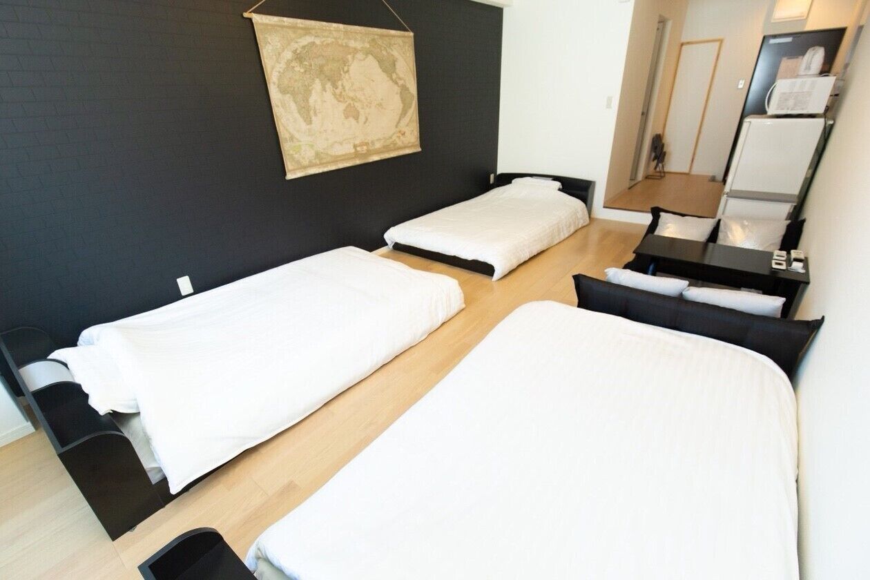A room with two single beds, a small desk with a chair, a mirror, and a map on the wall.