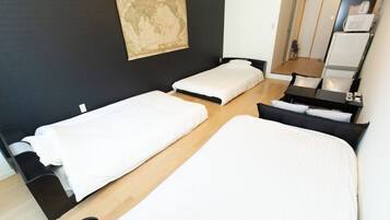 A room with two single beds, a small desk with a chair, a mirror, and a map on the wall.